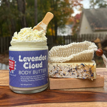 Jar of Lavender Cloud body butter with a wooden spatula and soap on a wooden soapdish.