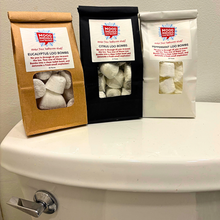 Three packages of Mood Indigo loo bombs on a toilet tank