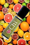 Fruity, Citrus essential oil roll on perfume bottle surrounded by colorful citrus fruits on a wooden surface. made by Mood Indigo