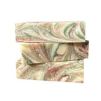 Three swirled grapefruit essential oil soap bars in green, pink, and beige on a white background