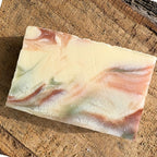 Bar of natural grapefruit soap with a marbled design on a wooden surface
