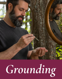 Man holding a patchouli beard oil in front of a mirror with 'Grounding' text overlay. Grounding collection by Mood Indigo