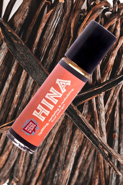 Bottle of Vanilla perfume oil in a roll on bottom nestled on several vanilla beans