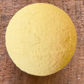 Mango and Yellow clay bath bomb on a wooden surface. Scented with Mango oil, made by Mood indigo