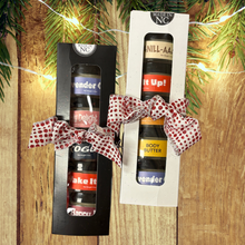 Two gift boxes with mini jars of Mood indigo body butters on a wooden surface with Christmas lights and decorations.