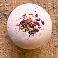 Sandalwood and rosewood bath bomb with dried rose petals on a wooden surface. scented with essential oils. Made by Mood indigo