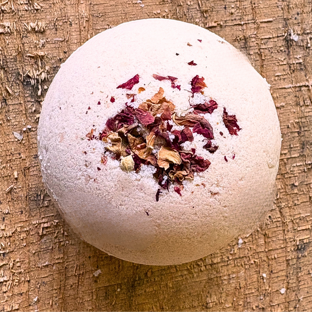 Sandalwood and rosewood bath bomb with dried rose petals on a wooden surface. scented with essential oils