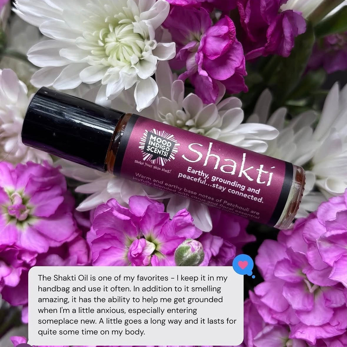 Shakti Patchouli essential oil perfume bottle surrounded by purple and white flowers with a user review.