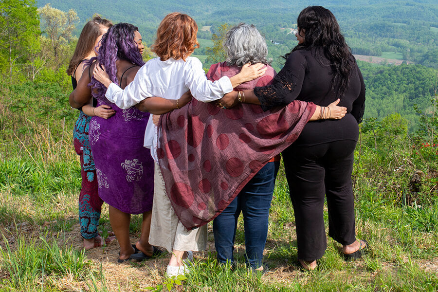 Five women standing together holding shoulders