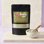 Mood Indigo Living EXOTIC-AH! 6 oz face mask pouch beside a ceramic bowl of green clay powder and a wooden spoon.