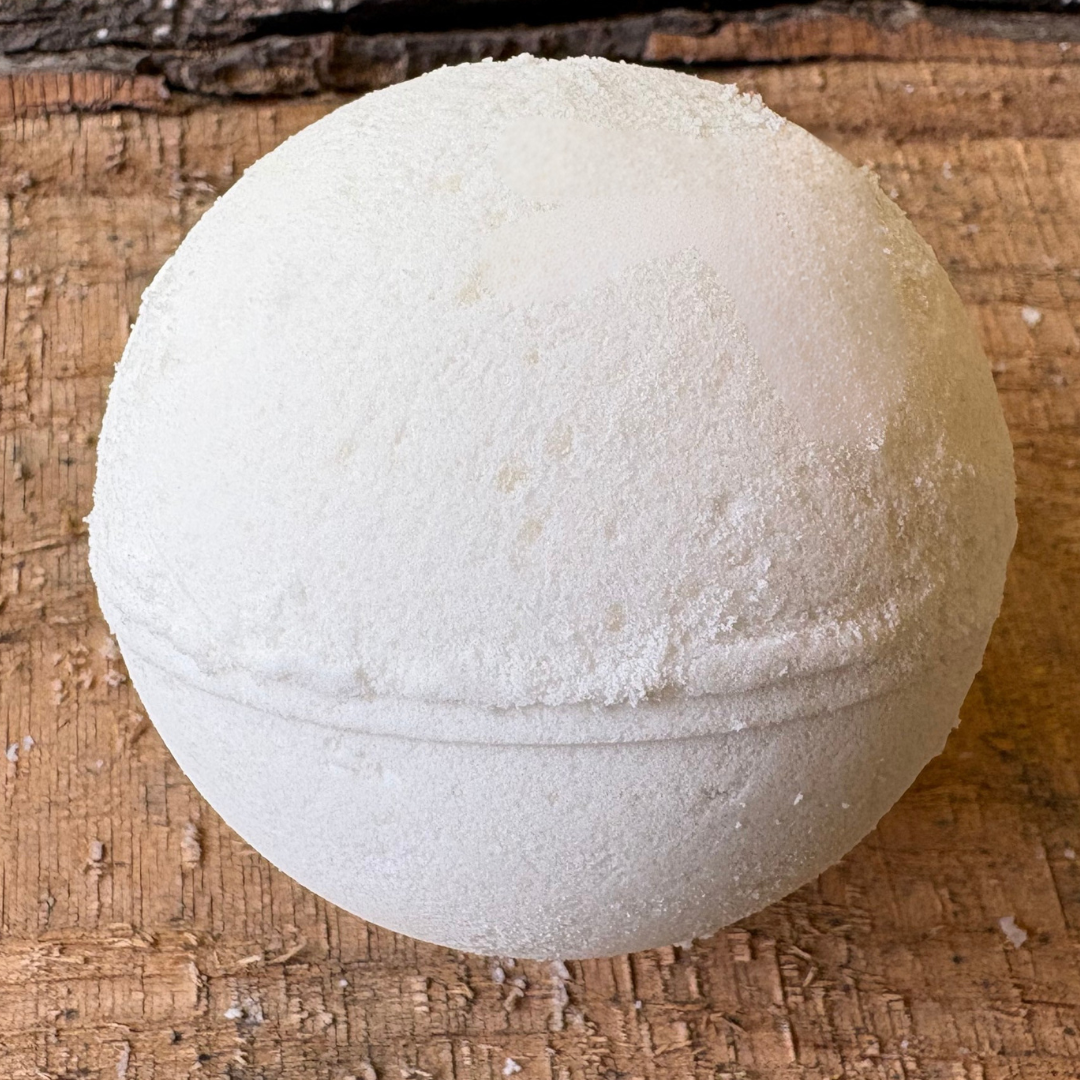 White Patchouli bath bomb on a wooden surface. Scented with patchouli essential oils and sweet orange, handmade in NC by Mood Indigo