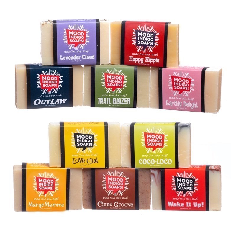A collection of colorful bar soaps with various scent names on labels, arranged in three rows.