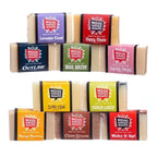 A collection of colorful bar soaps with various scent names on labels, arranged in three rows.