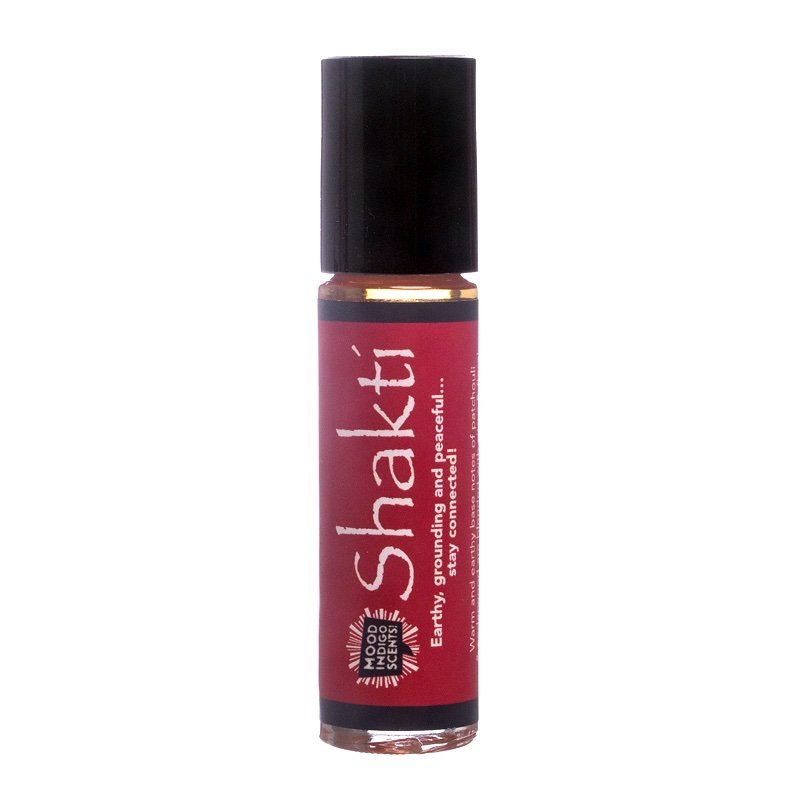 A small roller bottle of Patchouli Essential Oil Perfume labeled 'Shakti' by Mood Indigo, with a black cap and red label.